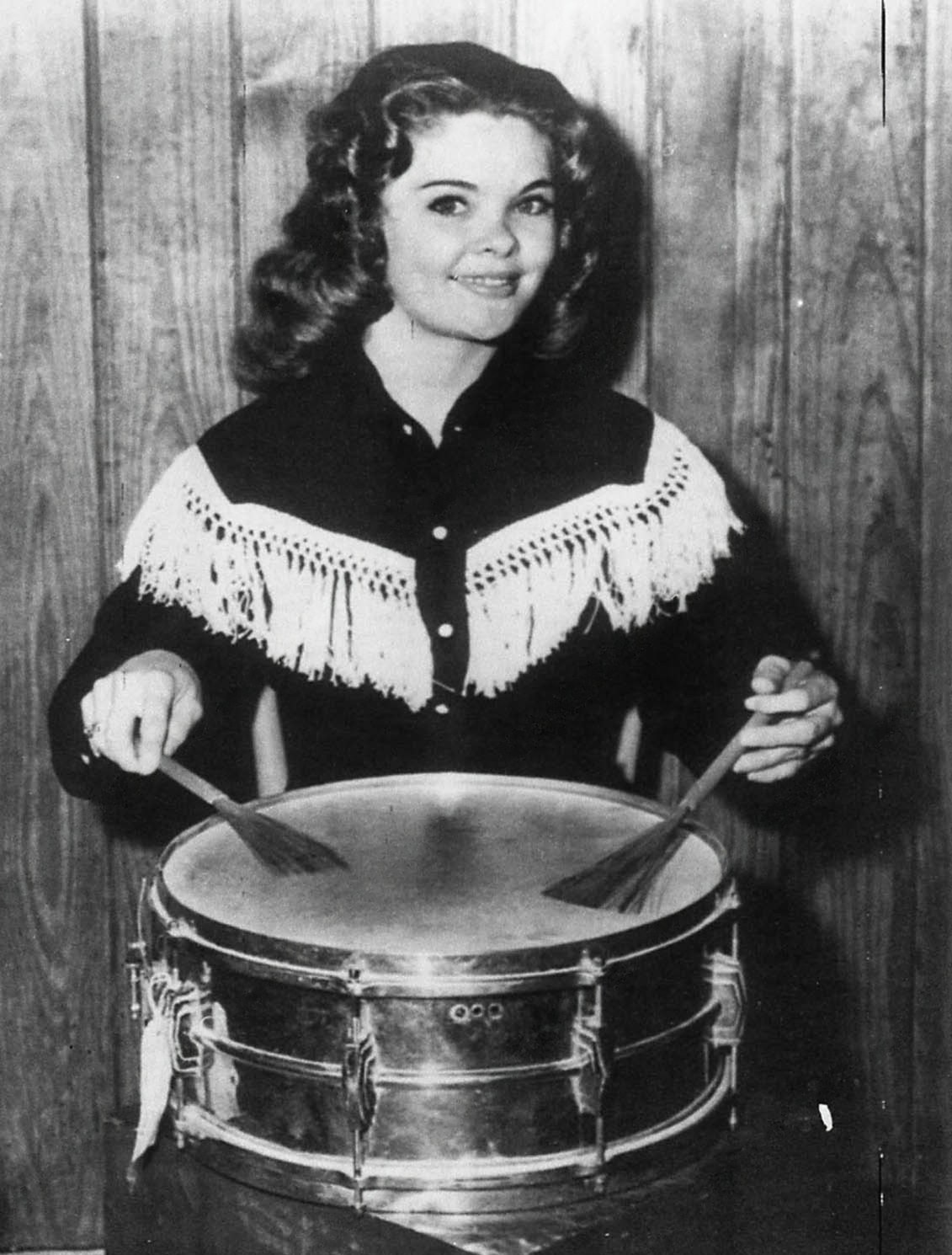 Candy Barr playing a snare drum at the Huntsville prison rodeo in 1960, in a fringed western shirt.